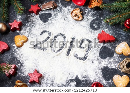 Happy New Year 2019 written on flour and Christmas Decorations Gingerbread cookies on dark stone background. New Year greeting card.