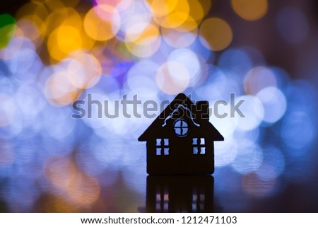 Silhouette of cute Christmas house with windows with colorful garland light bokeh on background. Concept of sweet home.