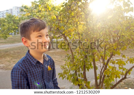 Happy boy have fun in the autumn park, throw up leaves, smie and laugh