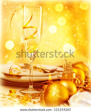 Picture of luxury festive table setting, closeup image of beautiful white utensil decorated with golden shiny balls and candle on blur glowing background, New Year eve, Christmas holiday dinner party