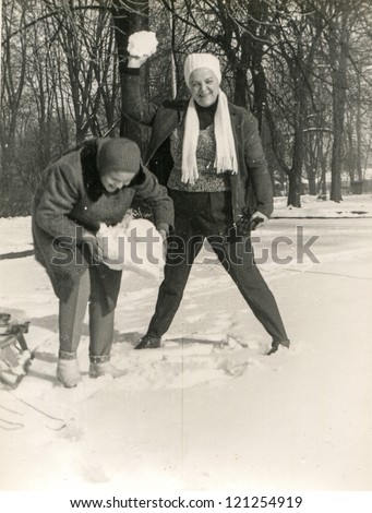 Vintage photo of mother and daughter playing with snowballs (sixties)