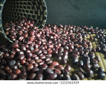 Soft focus of red beans on the top of bamboo table with dark background and flare light.