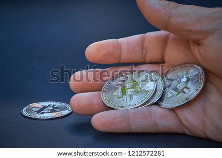 A silver Bitcoin is in the open hand. The coin shines and reflects light. The background is dark and abstract. The BTC currency is the symbol of a decentralized cryptocurrency.