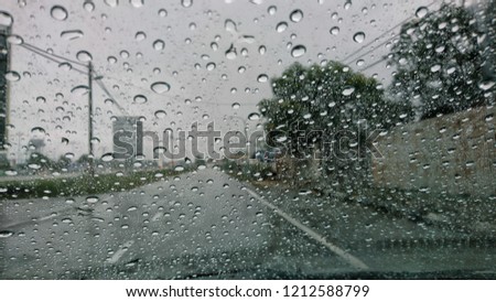 Driving car in the rain on wet road. Rainy weather through the car window. Rain through wind-screen of moving car. View through the car window in the rain.
