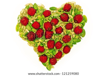 Pumpkin and sunflower seeds' kernel with dry haw forming heart shape on white background