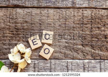 Inscription ECO letters word jasmine flower on old rustic wooden backdrop. Eco Village abstract environmental background. Nature protection energy saving ecology concept. Flat lay top view copy cpace
