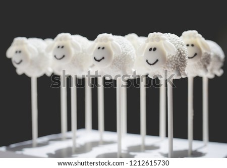 A set of happy sheep cake pops with a black background.