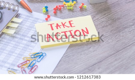Take action written on a blank notes and document on wooden background. Business concept