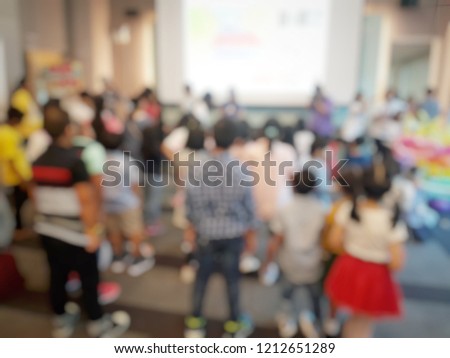 Blurred picture of a lot of children in an event. Children are dancing and watching at the screen. Event about children. Activity and recreation concept. Children day.