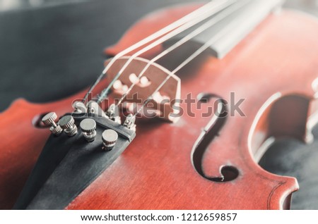 The violin on the dark table, Close - up of violin on the wooden floor, Top view of violin musical on dark wooden floor, Vintage and classic musical instrument used in the orchestra.