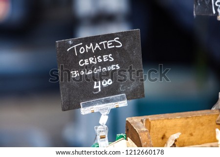Chalk sign selling organic cherry tomatoes in a french canadian farmer's market under the name tomates cerises biologiques