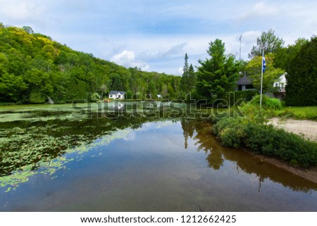 Calm lake with water lilies and chalets around - Wide angle picture taken in Quebec, Canada