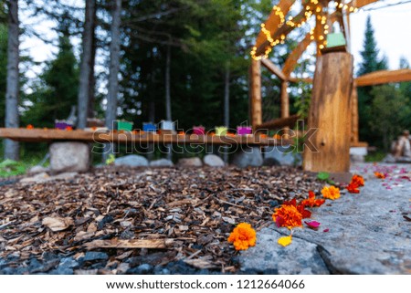 Wooden structure with various colors of silk lantern boats displayed and flower petals scattered on the floor all around - 2/2 - Wide angle picture taken outside in northern Quebec, Canada