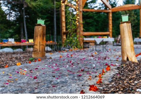 Wooden structure with various colors of silk lantern boats displayed and flower petals scattered on the floor all around - 1/2 - Wide angle picture taken outside in northern Quebec, Canada