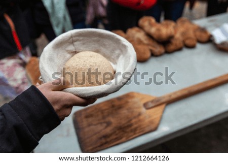 Man is holding a ready to cook bread dough, in front of a table full of freshly cooked loaves of bread - Pictures taken during a bread and pizza making workshop