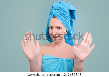 Enough. Beautiful young woman emerged from the bath after a spa procedure in a towel on her head is not satisfied with the service on a blue background. Advertising space
