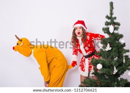 Holiday, Christmas and joke concept - Couple in Christmas costume fooling around together on white background