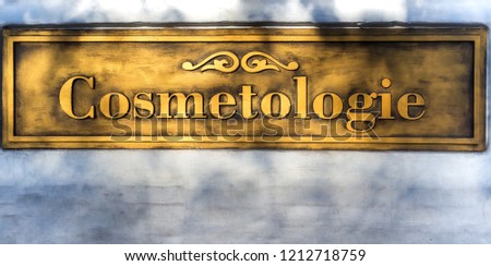 Gold embossed inscription Cosmetology on the white wall.