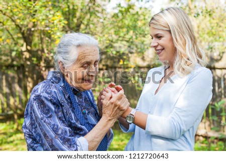 Picture of elderly woman in blue dress spending quality time with beautiful granddaughter