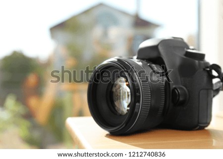 Professional camera on wooden table against blurred background, space for text. Photographer's equipment