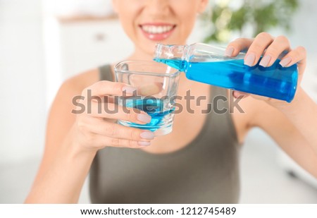 Woman pouring mouthwash from bottle into glass, closeup. Teeth care Royalty-Free Stock Photo #1212745489
