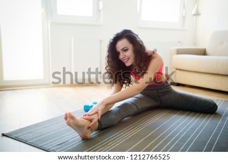 Young attractive sportswoman doing exercises at home