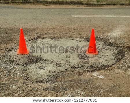 Damaged road with red cone warning