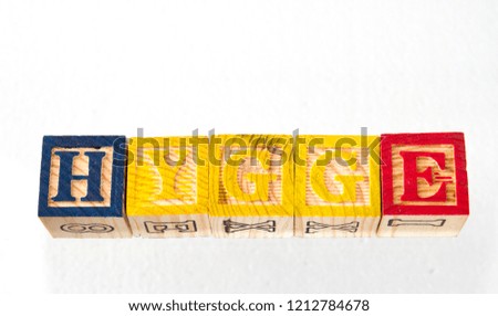 The term hygge visually displayed on a white background using colorful wooden toy blocks image with copy space in landscape format