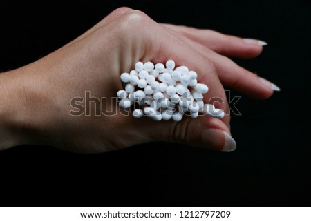 White cotton buds in hand on a black background