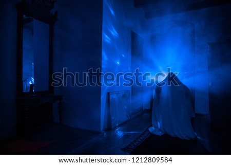Horror silhouette of ghost inside dark room with mirror. Scary halloween concept. Silhouette of witch inside haunted house with fog and light on background. Selective focus