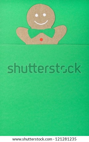 handmade of paper cut out gingerbread man under green background in vertical