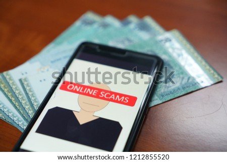 Online scams using smartphones and social networks. Conceptual photo using phone and Malaysian currency. Selective focus.