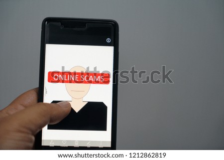 Conceptual photo using smartphone and office out of focused background. It is all about online scams.