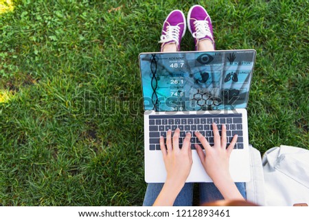 cropped image of woman using laptop with medical appliance in park