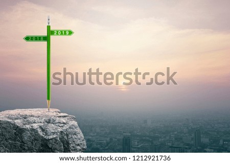 2019 and 2018 direction sign plate with green pencil on rock over aerial view of cityscape at sunset, vintage style, Business success strategy planning concept, Happy new year 2018 calendar cover