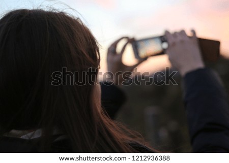the girl photographs a sunset on phone