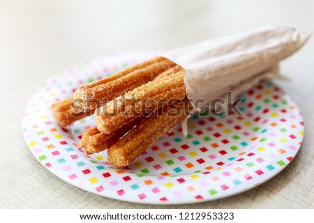 homemade churros in a plate for summer party  Royalty-Free Stock Photo #1212953323
