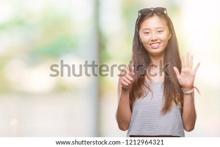 Young asian woman wearing sunglasses over isolated background showing and pointing up with fingers number six while smiling confident and happy.