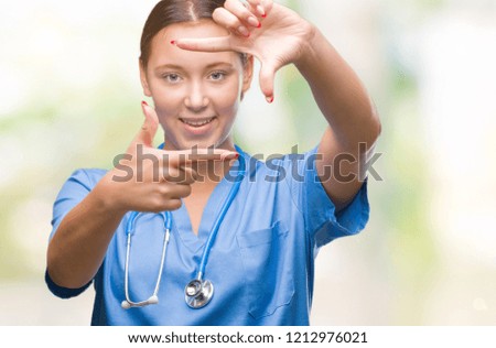 Young caucasian doctor woman wearing medical uniform over isolated background smiling making frame with hands and fingers with happy face. Creativity and photography concept.
