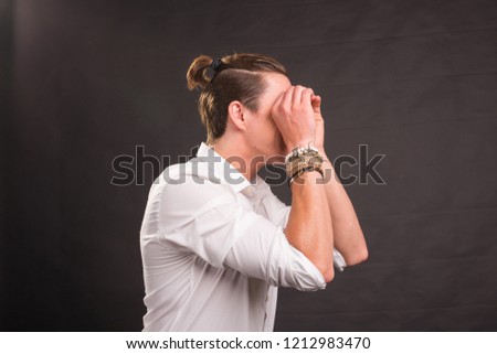 Handsome man holding hands near eyes, imitating glasses over black background. Guy fools around
