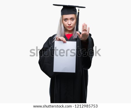 Young blonde woman wearing graduate uniform holding degree over isolated background with open hand doing stop sign with serious and confident expression, defense gesture