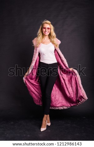 Fashion and beauty concept - beautiful blond model posing over dark background