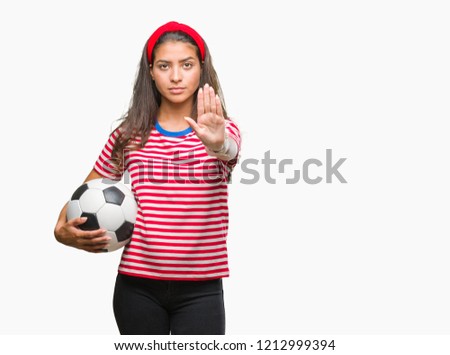 Young beautiful arab woman holding soccer football ball over isolated background with open hand doing stop sign with serious and confident expression, defense gesture