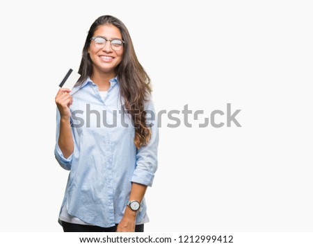 Young arab woman holding credit card over isolated background with a happy face standing and smiling with a confident smile showing teeth