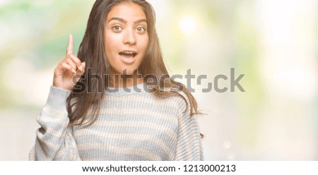 Young beautiful arab woman wearing winter sweater over isolated background pointing finger up with successful idea. Exited and happy. Number one.