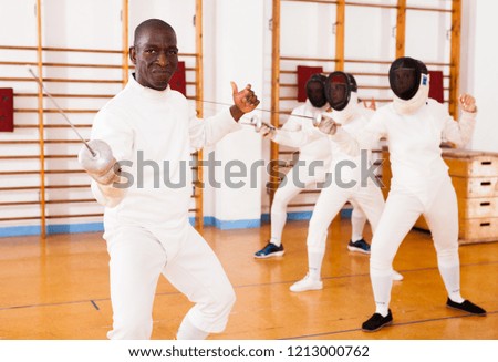 Sporty african american man fencer practicing effective fencing techniques in training room 



