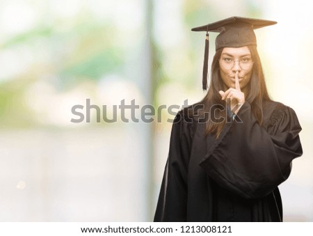 Young hispanic woman wearing graduated cap and uniform asking to be quiet with finger on lips. Silence and secret concept.