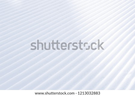 Background of diagonal geometrical parallel stripes of snow with light shadow