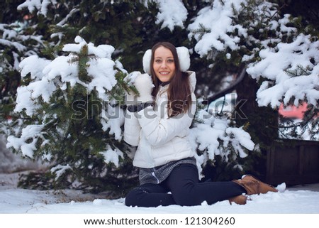 brunette woman sitting  in winter park under fur tree