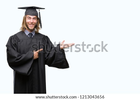 Young handsome graduated man with long hair over isolated background amazed and smiling to the camera while presenting with hand and pointing with finger.